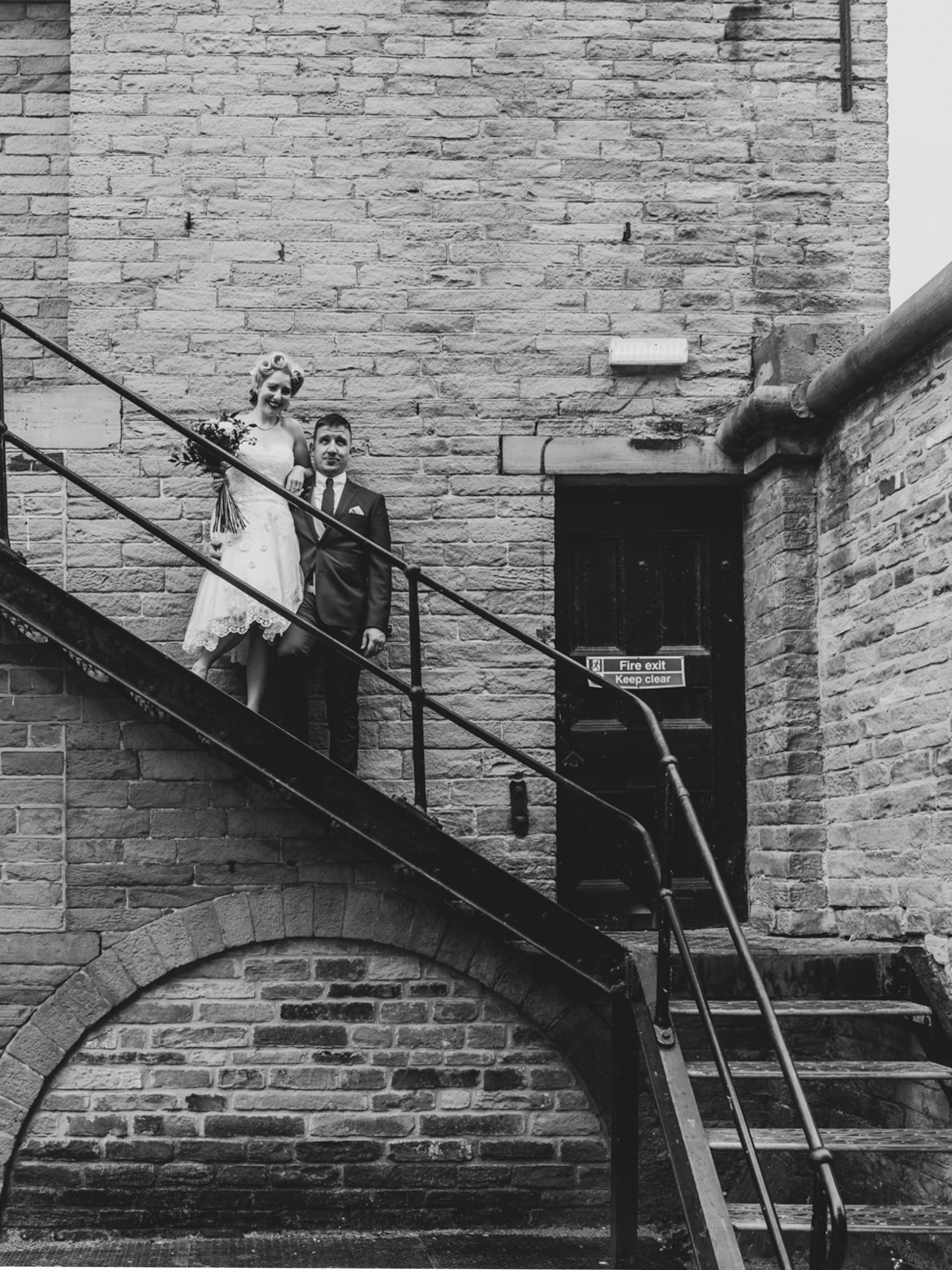 Documentary style wedding photographer in Leeds. Couple pose on stair case at Yorkshire Mill near The Arches, Halifax