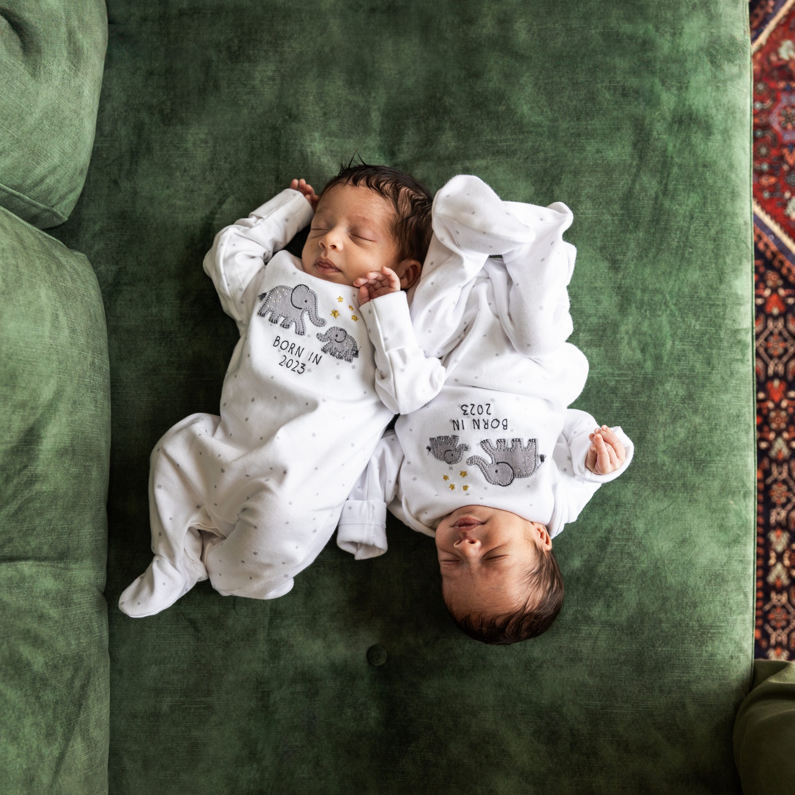 Newborn twins top and tail on green sofa, laid back newborn photography in their own home