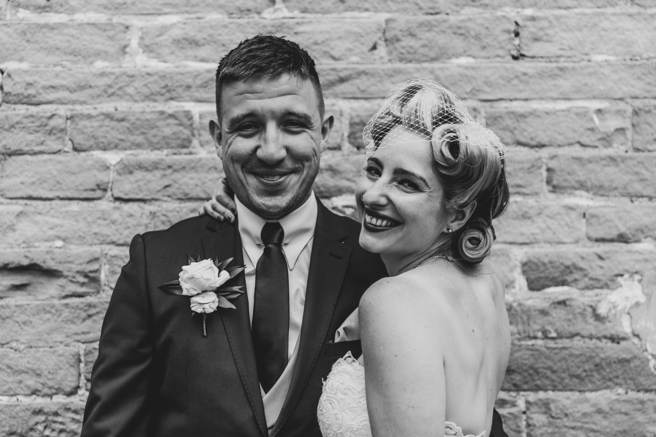 Bride and Groom pose against wall in Yorkshire Mill, The Arches, Halifax